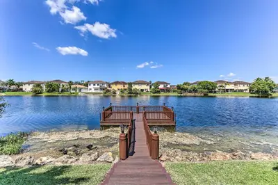a wooden bridge over a large lake with houses at Spacious Miami Retreat with Grill, Pool and Dock! in Miami