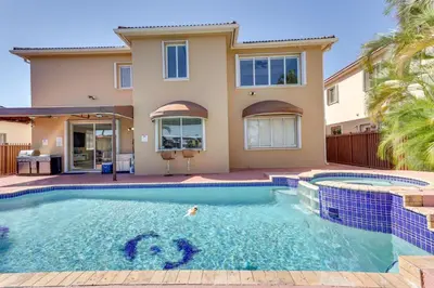 a villa with a swimming pool in front of a house at Spacious Miami Retreat with Grill, Pool and Dock! in Miami