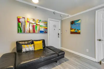 a leather couch in a living room with paintings on the wall at Sunny Miami Beach Condo Steps to Boardwalk! in Miami Beach