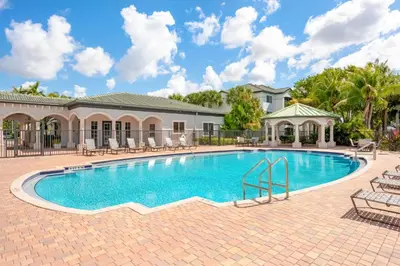 a swimming pool with chairs and a house at Tucker at Palm Trace Landings Fort Lauderdale in Davie