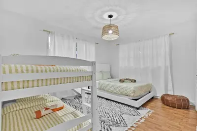a white bedroom with two bunk beds and a rug at Private Lakefront Home in Miami/Pembroke in Pembroke Pines