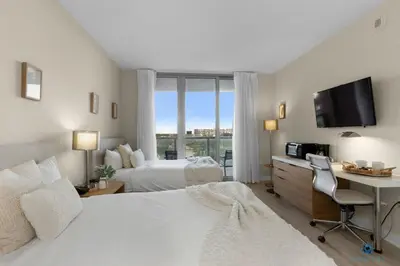 a bedroom with two beds and a desk with a computer at Spectacular View with Balcony, Pool, Near Beach in Hallandale Beach