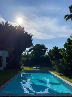 a blue swimming pool with the sun in the background at Miami guest house with large pool in Miami