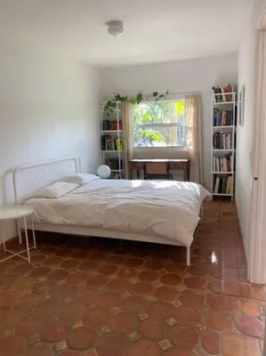 a bedroom with a bed and a window and book shelves at Miami guest house with large pool in Miami