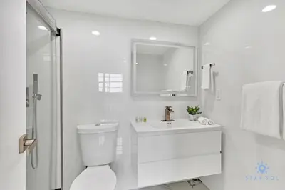 a white bathroom with a toilet and a sink at Special Offer - Balcony - Beachfront Condo - Gym in Hollywood