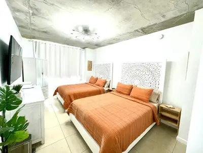 two beds in a small room with orange sheets at Beautiful 1BD 1BTH at Midblock FREE PARKING in Miami