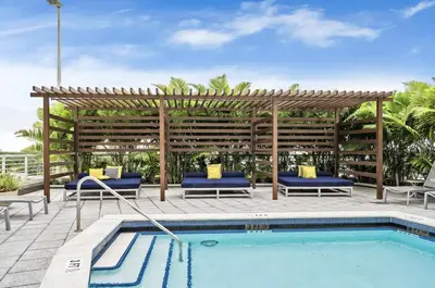 a swimming pool with a wooden pergola and blue chairs and a pool at Beautiful 1BD 1BTH at Midblock FREE PARKING in Miami