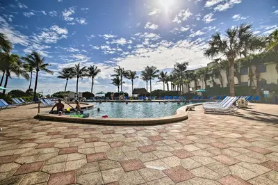 a swimming pool with palm trees in a resort at Ocean-View Balcony Beachfront Hollywood Apt! in Hollywood