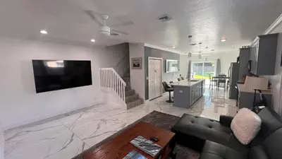a living room with a couch and a tv on a wall at Luxe Fort Lauderdale in Fort Lauderdale