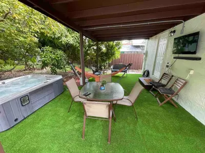 a patio with a table and chairs and a hot tub at “La Casita” Beautiful home in the heart of Miami ! in Miami