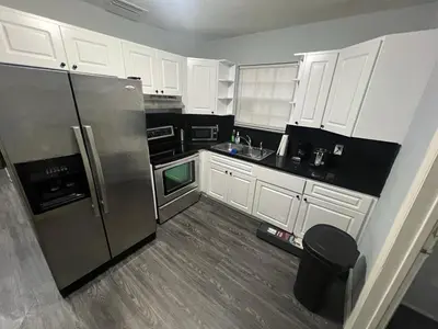 a kitchen with white cabinets and a stainless steel refrigerator at “La Casita” Beautiful home in the heart of Miami ! in Miami
