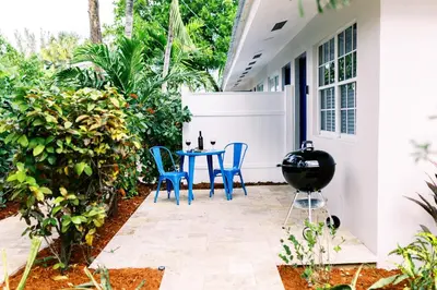 a patio with blue chairs and a table on a house at Casa Cordova Apartments By Lowkl in Fort Lauderdale