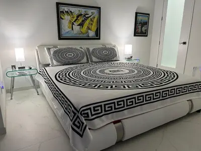 a bedroom with a large bed with two tables and a painting at Men only clothing option guesthouse near Wilton Manors in Fort Lauderdale