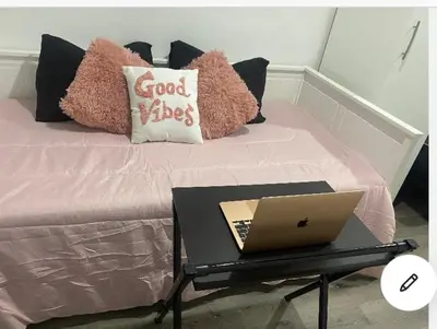 a bed with a laptop on a table next to it at Tiny place w private hot jacuzzi 7 min to Miami international airport in Miami