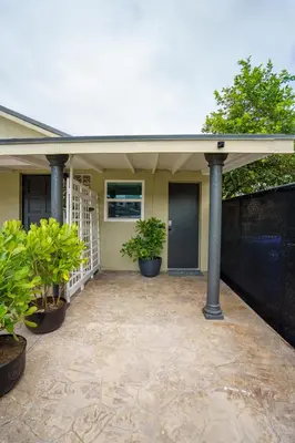 a house with a porch with two potted plants at Cozy Studio w/gated parking in Miami
