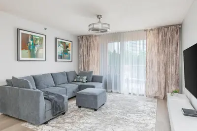 a living room with a gray couch and a large window at Spacious 3 Bedroom Condo in Aventura in Aventura