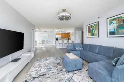 a living room with a blue couch and a flat screen tv at Spacious 3 Bedroom Condo in Aventura in Aventura