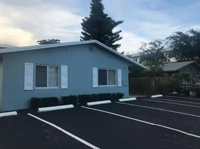 a parking lot with a blue building and a tree at The Guesthouse 3 - Wilton Manors in Fort Lauderdale