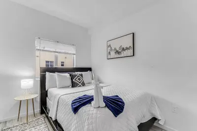 a white bedroom with a bed with blue and white sheets at Lovely Unit Mins from Wynwood with Free Parking in Miami
