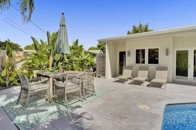 a patio with a table and chairs and a pool at Brand New! Heated Pool, Golf Cart, Next to Beach in Fort Lauderdale