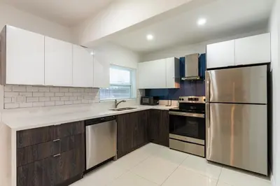 a kitchen with wooden cabinets and stainless steel appliances at Beautiful, fully furnished 2bed 1bath house - 5 minute walk to Miracle Mile Downtown Coral Gables in Miami