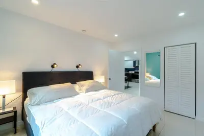 a white bedroom with a large bed with white sheets at Beautiful, fully furnished 2bed 1bath house - 5 minute walk to Miracle Mile Downtown Coral Gables in Miami