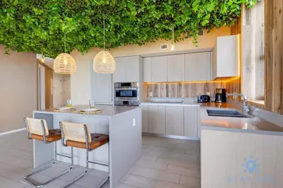 a kitchen with white cabinets and a counter with chairs at Jungle Experience, High Floor, Pools in Hollywood