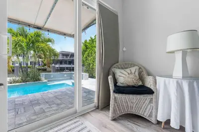 a room with a chair and a table with a lamp at Casa Flamingo Intracoastal Front with Heated Pool in Fort Lauderdale