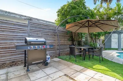 a grill and a table with chairs and an umbrella at Hollys Hacienda with Heated Pool and Patio Area in Hollywood