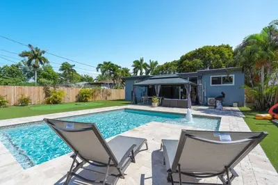 a swimming pool with two chairs and a house at Wileys Paradise Three Bedroom Two Bath plus Office and Heated Pool in Hollywood