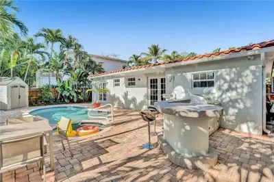 a home with a swimming pool and a house at Chic Victoria Park Villa with Heated Pool and Spa in Fort Lauderdale