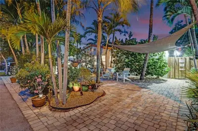 a patio with palm trees and a hammock and plants at Chic Victoria Park Villa with Heated Pool and Spa in Fort Lauderdale