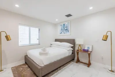 a bedroom with a bed with white walls and a window at Olas Villa by Rove Travel - Home with Heated Pool in Fort Lauderdale