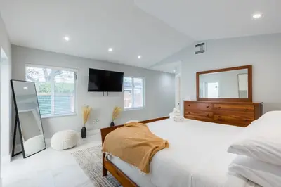 a bedroom with a large bed and a mirror at Olas Villa by Rove Travel - Home with Heated Pool in Fort Lauderdale