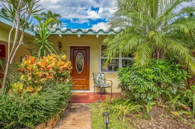 a yellow house with a chair and palm trees at Beautiful Comfy Home With Private Hot Tub Close To Beach home in Fort Lauderdale