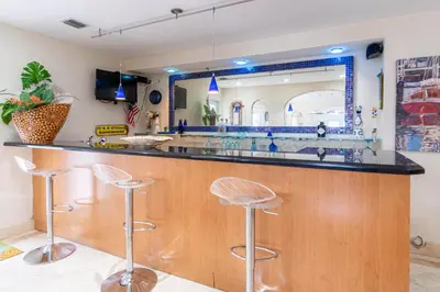 a kitchen with a bar with stools and a mirror at Oceana Blue / Beach Front / Pool / Bar / Relax in Fort Lauderdale
