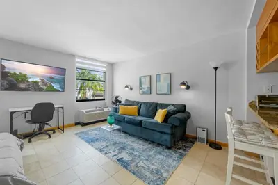 a living room with a blue couch and a window at Cozy studio, walk to the beach, restaurants, bars in Miami Beach