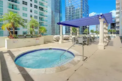 a hot tub in a patio with a blue umbrella at Elegant 1BR APT w balcony and stunning bay view in Miami