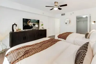 two beds in a white room with a ceiling fan at Elegant 1BR APT w balcony and stunning bay view in Miami