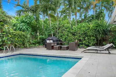 a swimming pool with chairs and a table at Modern 4BR Villa with Pool - Outdoor amenities - WFH in Fort Lauderdale