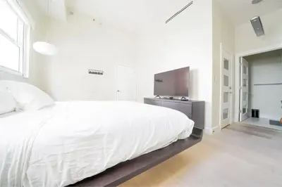 a white bedroom with a white bed and a television at Ocean view Work from Home Balcony Parking Pool in Miami