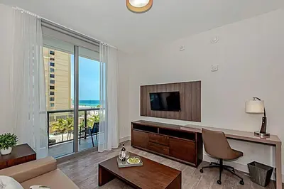 a living room with a tv and a couch and a table at Rooftop Pool - Ocean View Balcony - Hollywood Beach in Hollywood