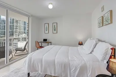 a white bedroom with a bed and a balcony at 2 Bedroom, 2 Bathroom plus Den Brickell Condo Pool, Hot Tub, and Gym in Miami