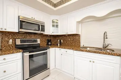 a kitchen with white cabinets and a sink and a microwave at Waterfront 2-Story Villa with Heated Pool in Pembroke Pines