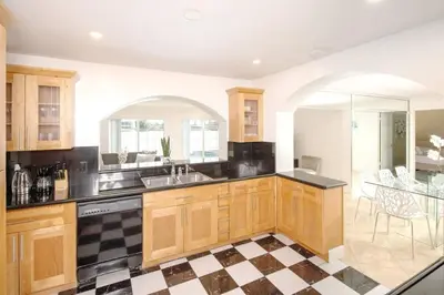 a kitchen with wooden cabinets and a checkered floor at Stunning Lake-Front Villa with Pool & Spa in Pembroke Pines