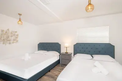 two beds in a bedroom with white walls at Stunning Lake-Front Villa with Pool & Spa in Pembroke Pines