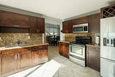 a large kitchen with wooden cabinets and appliances at Beautiful 7-Bedroom Villa with Pool in Hialeah