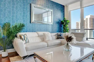 a living room with a white couch and a mirror at Lux 2BR Condo in Ocean Reserve with Pools and Tennis Courts in Miami Beach