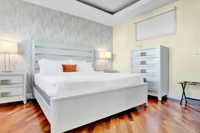 a white bedroom with a large white bed and a dresser at Lux 2BR Condo in Ocean Reserve with Pools and Tennis Courts in Miami Beach