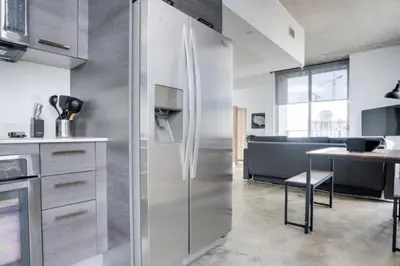 a kitchen with a stainless steel refrigerator and a table at Sun-Splashed 1BR Condo unit in DWTN Miami with WFH in Miami
